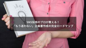デスクで企画書を作成する人物の画像。SNS採用のロゴと、矢印で進む道が描かれている。